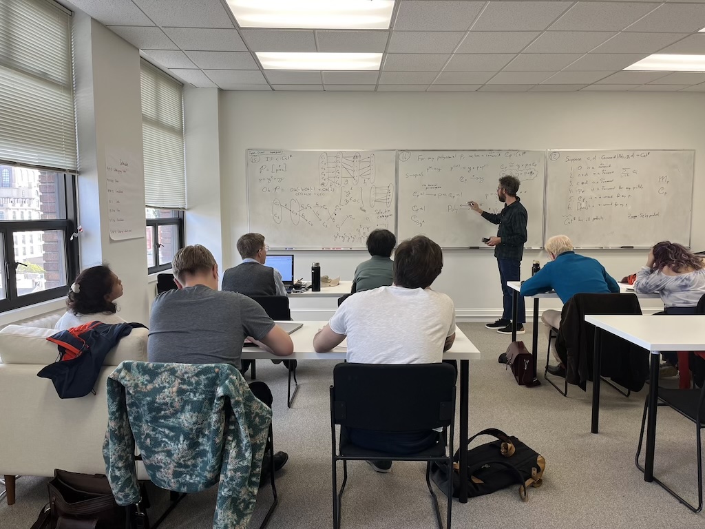 David Spivak at a whiteboard lecturing to the participants